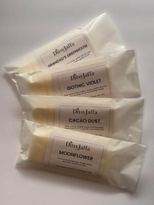 Four DitsyJaffa wax melt snap bars in glassine bags containing Grandad's Greenhouse, Gothic Violet, Cacao Dust and Moonflower scents, showing the hand-poured coconut and rapeseed wax details on the labels.